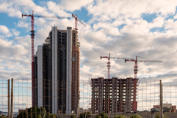 Fototapeta na wymiar Two skyscrapers under construction with four red cranes.