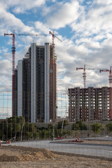Two skyscrapers under construction with red cranes.
