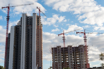 Low-angle shot of two skyscrapers under construction with red cranes.