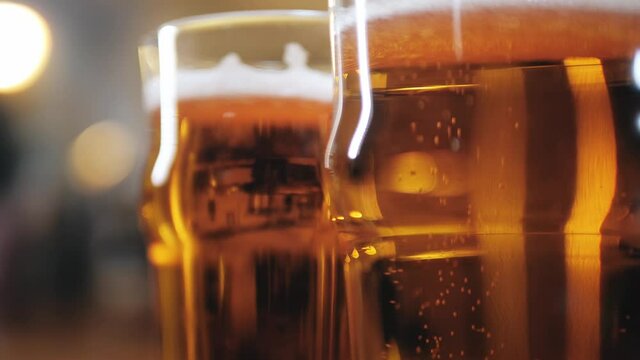 Foamy beer in glasses close-up. Alcohol golden beer drink in mugs. Macro shooting of fresh pale ale on bar counter background in pub. 