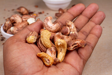 Roasted cashew nuts in hand on light background isolation.