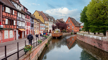 Colmar village, in Alsace, France. Identified tourists walking along the river Lauch in Little Venice district, during an overcast day. 