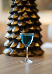 glass with a blue drink on the background of a Christmas tree