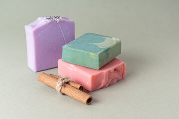 Set of natural handmade soap and cinnamon sticks on green background. Soap with different smells. Space for text