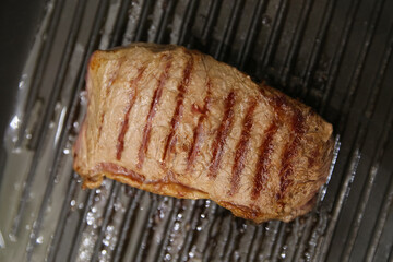 blurred steak beef meat fried in a grill pan, medium roast meat
