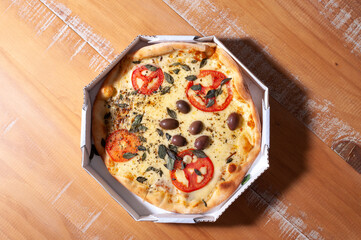 Top view of opened pizza box containing a "margherita" pizza on wooden table.