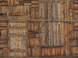 Old wooden wall with boarded up door and window. Dark wooden natural background with traces of paint. Texture. Place for your text