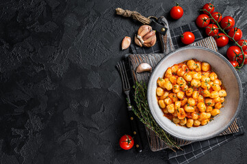 Gnocchi potato pasta with tomato sauce and thyme. Black background. Top view. Copy space