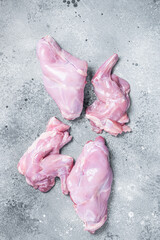 Raw rabbit legs slices on a butcher board. Gray background. Top view