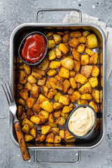 Patatas bravas traditional Spanish potatoes snack tapas in a steel tray. Gray background. Top view