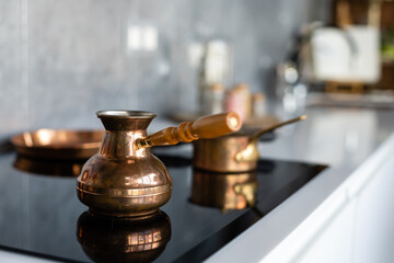 Set of saucepans hanging in kitchen. Hanging Copper kitchen utensil on the white wall. Different kind of vintage copper cookware, pans, pots and funnel on wooden kitchen. Rustic kitchen interior decor