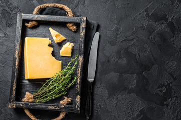 Swiss Hard cheese piece in wooden tray. Black background. Top view. Copy space