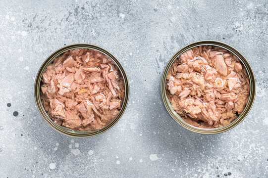 Open tin can with canned tuna fish. Gray background. top view