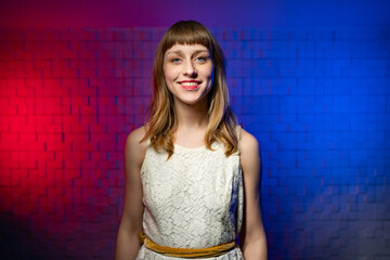 A young friendly cute girl with brown hair, bangs in a white dress looks into the camera and smiles...