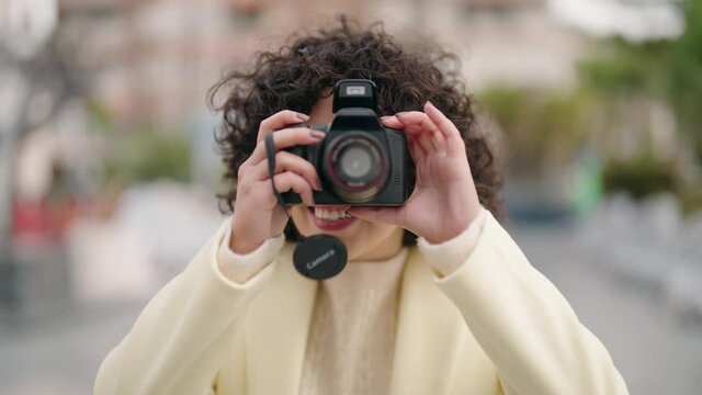 Young woman smiling confident using professional camera at street