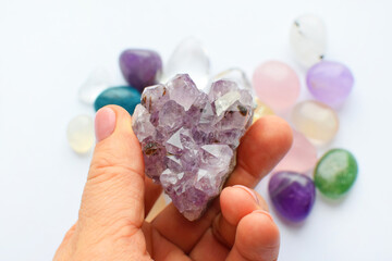 Beautiful purple crystals of amethyst in hand. Druse amethyst in the shape of a heart on the...