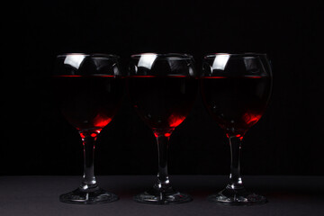 Three glasses of red wine on a black background. Alcoholic drink.