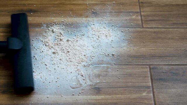 Remove spilled bulk mixture on the floor. A man vacuums the floor tiles. Cleaning the room with a vacuum cleaner.