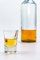 Alcoholic drink in a glass and bottle of brandy in the back on white table. Of strong alcoholic intoxication. The concept of alcohol dependence. Alcohol intoxication.