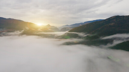 sunrise over mountains with many clouds, drone view