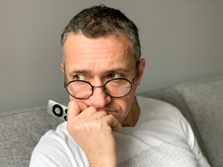 Middle aged man is spending holiday at home. Looked bored of streaming tv and reading book. Self...