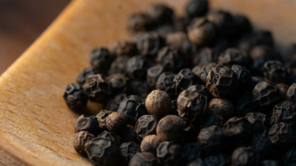Fresh Black Peppercorns on a wooden Spoon