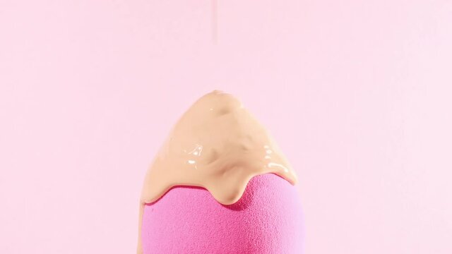 Make-up liquid beige foundation pouring on sponge, closeup. Cosmetic Dripping bb Cream on makeup brush on pink background. Macro Shot. Beautiful Makeup concept. High quality 4k footage
