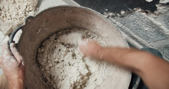 First Person View POV Of Young Man Construction Worker Hands Closeup Drops Gravel To Cement Mortar And Mixing It. Concept Of Home Repair And Renovation. 