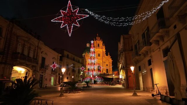 alt flying under Christmas decor towards church at end of piazza in Ragusa Ibla