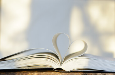he open book lies on the table. The pages are folded in the shape of a heart. Concept of love for literature