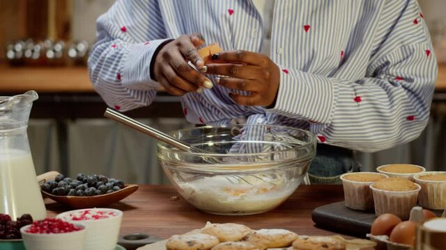 African american chef cooking biscuits. Confectioner woman preparing ingredients for cookies, adding aggs into flour in bowl and mixing, making dough. Baking food, homemade treats. Bakery at home.