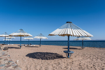 wooden beach umbrellas and sun loungers by the red sea in bright sunny day