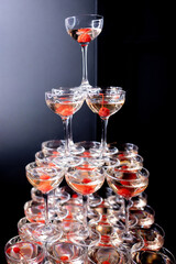 Champagne pyramid with cherries in dark colors close-up