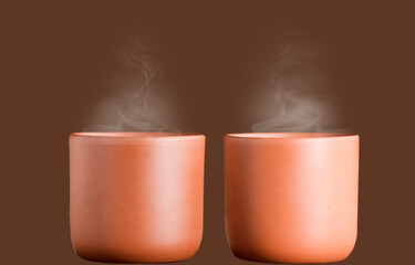 two ceramic clay cups with coffee or chocolate, isolated with brown background