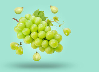 Sweet Green grape with leaves falling in the air isolated on green background, Shine Muscat Grape on green background With clipping path.