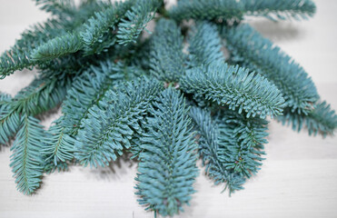 Naklejka na ściany i meble branches of blue spruce lie on the light surface of a wooden table. Winter decor, sprigs of blue spruce, illegal logging