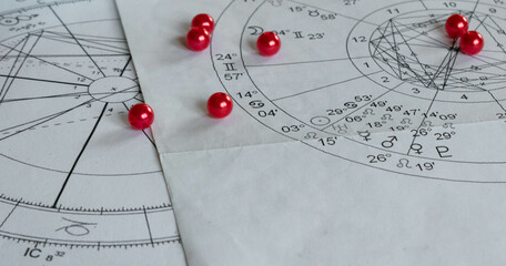Detail of printed astrology natal charts with red pearls; copy space