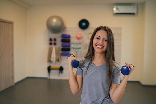 Young Attractive Woman Using Small Dumbbells While Training In The Gym