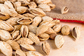 Roasted brown almond nuts in cracked shell on light table background ready to eat.