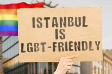 The phrase " Istanbul is LGBT-Friendly " on a banner in men's hand with blurred LGBT flag on the background. Human relationships. different. Diverse. liberty. Sexuality. Social issues. Society