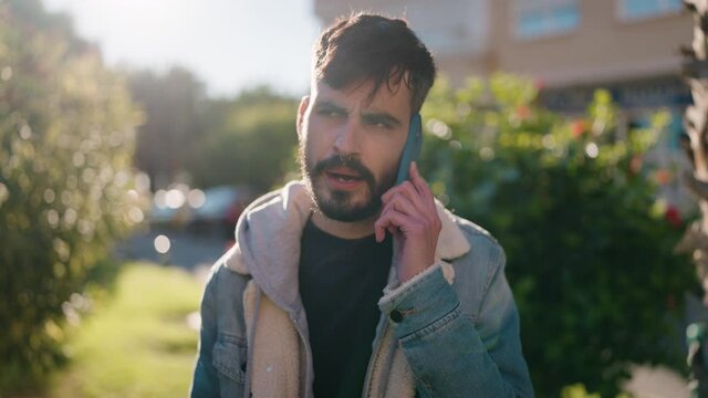 Young hispanic man smiling confident talking on the smartphone at park