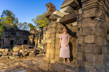 A girl in the ruins of Ta Prohm temple in Angkor complex, overgrown by trees, Cambodia