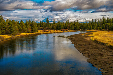 2021-12-24 THE DESCHUTES RIVER WINDING THROUGH SUNRIVER OREGON WITH MUDDY BANKS BRIGHT GRASS AND...