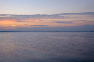 早朝、兵庫県芦屋市芦屋浜より大阪湾、西宮浜方面を臨む。空がオレンジ色に染まり大阪南港のビル群がシルエットで浮かぶ