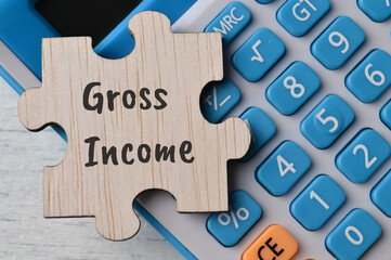 Calculator and wooden puzzle with text GROSS INCOME