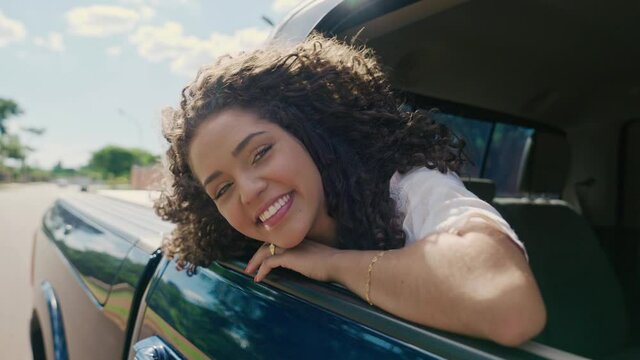 Latin woman in car window. Car trip. Curly hair in wind. Girl looks out of car window. Brazilian travel concept by car. Cinematic 4K