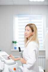 Beautiful woman doctor is standing in a modern equipped beauty salon holding a carbon peeling tool in her hand