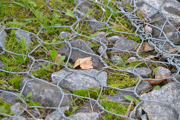 Gabion wall with gabion baskets and gabion stones in the park in autumn, retaining wall.