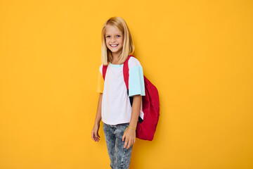 smiling school girl with a red backpack yellow color background
