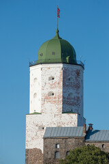 The tower of St. Olaf is close-up against the background of a blue cloudless sky. Vyborg Castle....